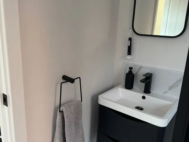 Small bathroom with a wall-hung black vanity unit, white basin, black tap and a black-framed mirror