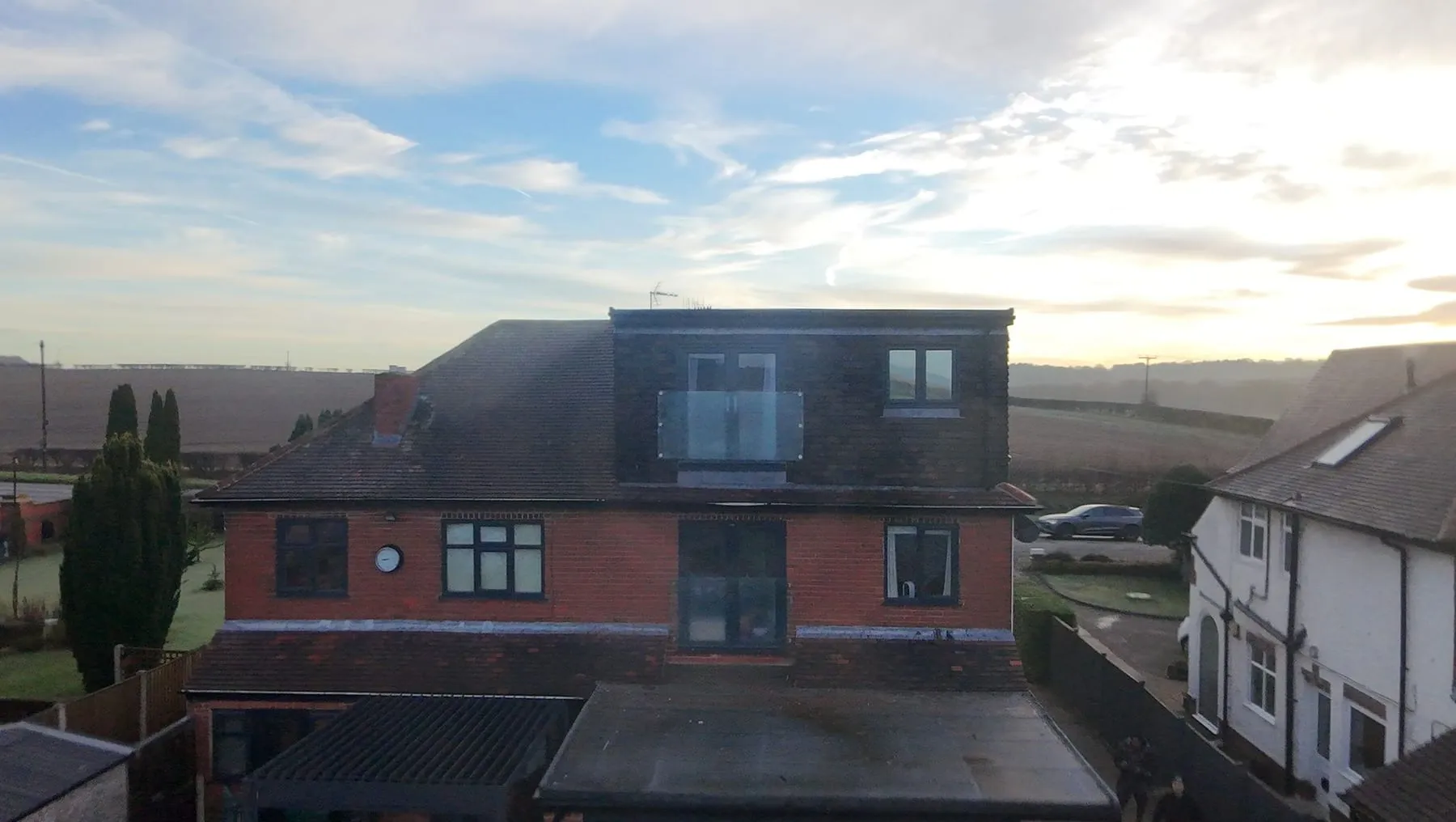Red-brick semi-detached house with a tile-hung rear dormer and glass Juliet balcony, seen from above