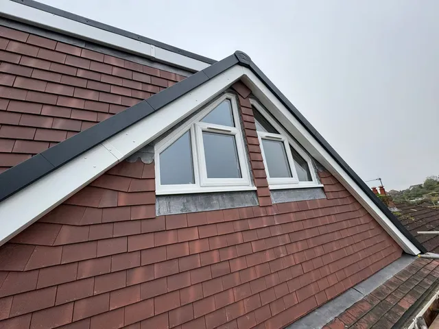 New gable clad in red clay hanging tiles with white bargeboards and a pair of white windows whose top panes follow the roof pitch