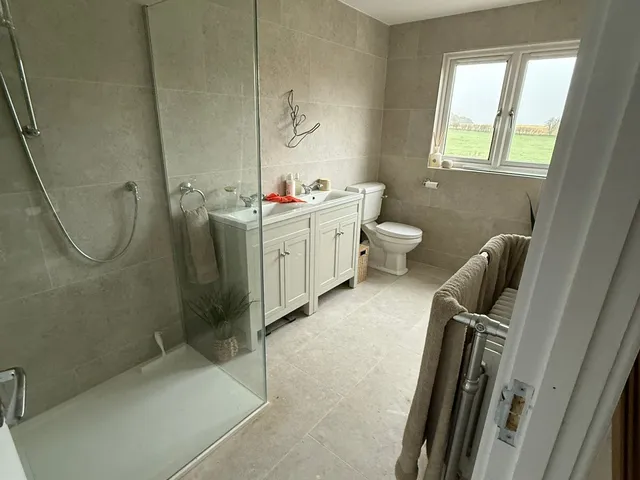 Loft shower room with a walk-in rainfall shower, stone-effect tiles, grey vanity unit and heated towel rail