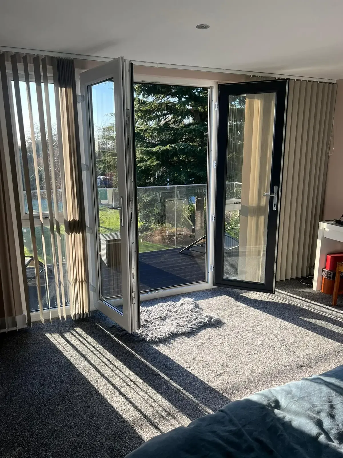 Sunlit loft bedroom with French doors open onto a glass balcony