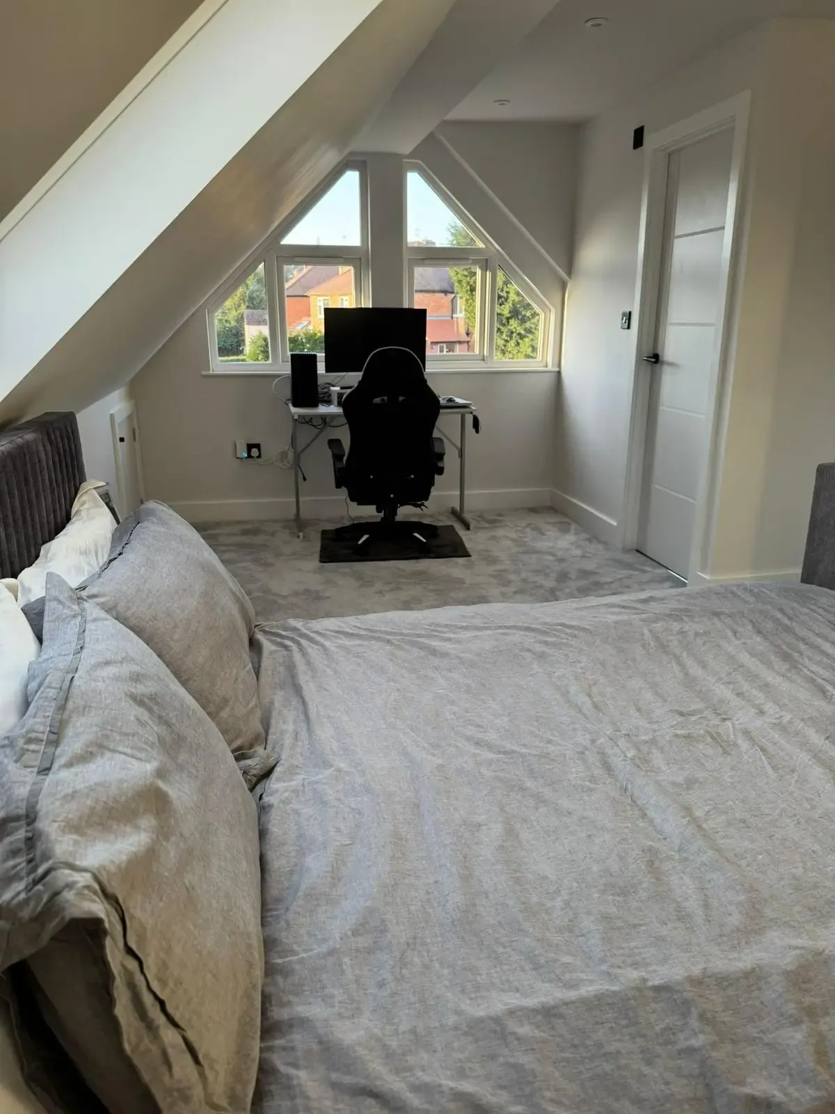 Loft bedroom with a sloping ceiling and a desk beneath a triangular gable window