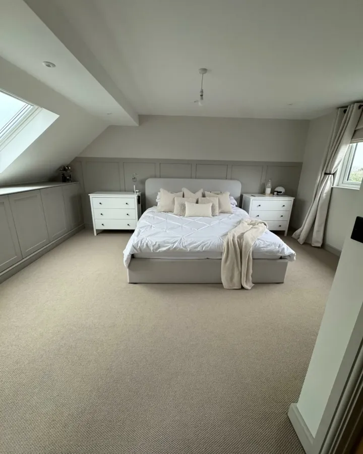 Loft bedroom with a roof window above a double bed and white bedside drawers