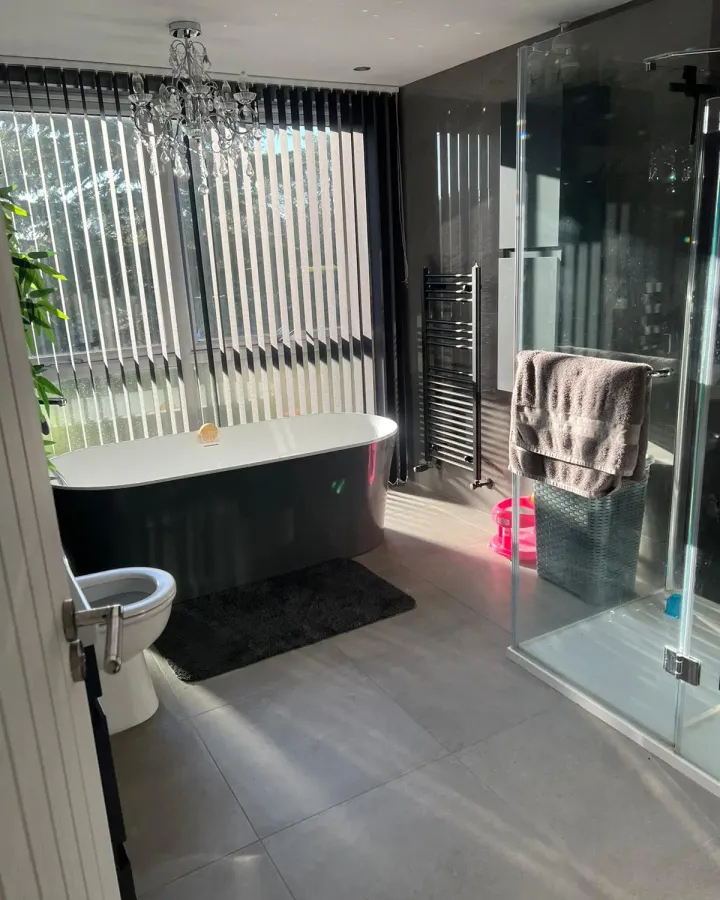 En-suite bathroom with a freestanding black bath, glass shower enclosure and chandelier
