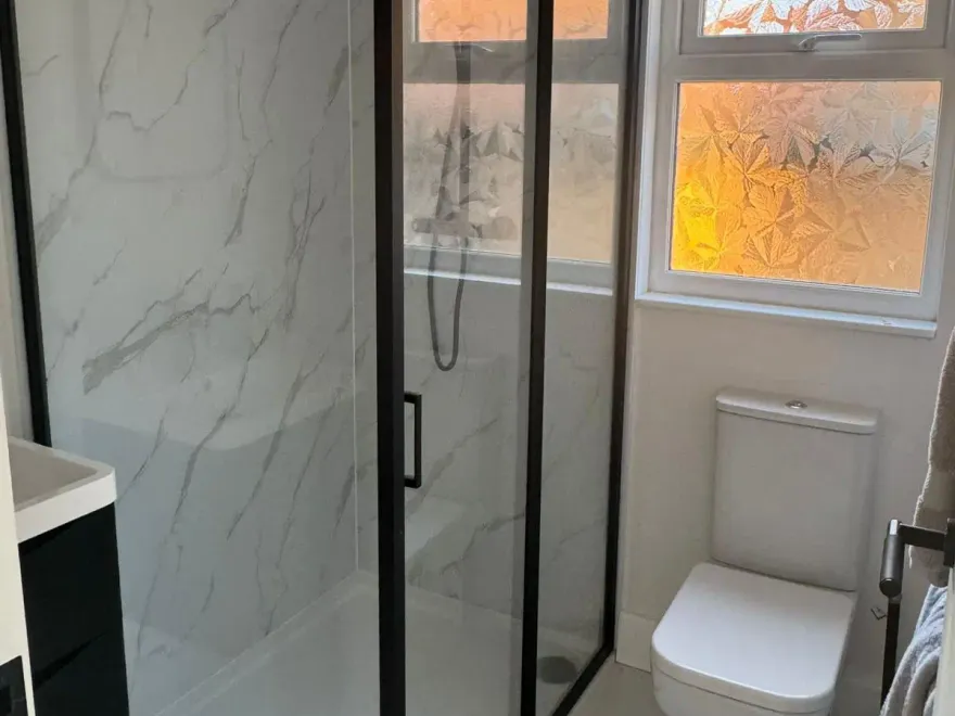Finished loft shower room with a black-framed glass shower enclosure and marble-effect wall panels