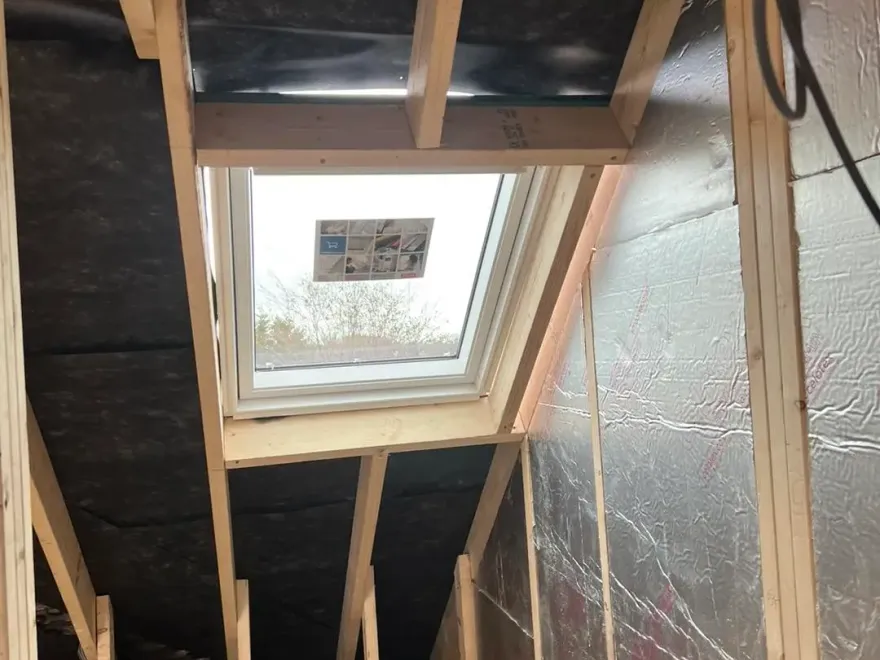 Foil-backed insulation fitted between timber framing around a new roof window